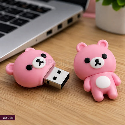 Two pink 3D bear-shaped USB flash drives on a wooden desk next to a laptop, with one flash drive shown partially unplugged.