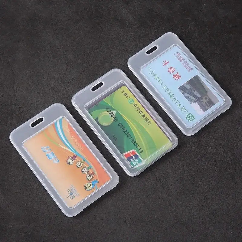 Three clear plastic ID card holders displaying different cards, laid out side by side on a dark background.