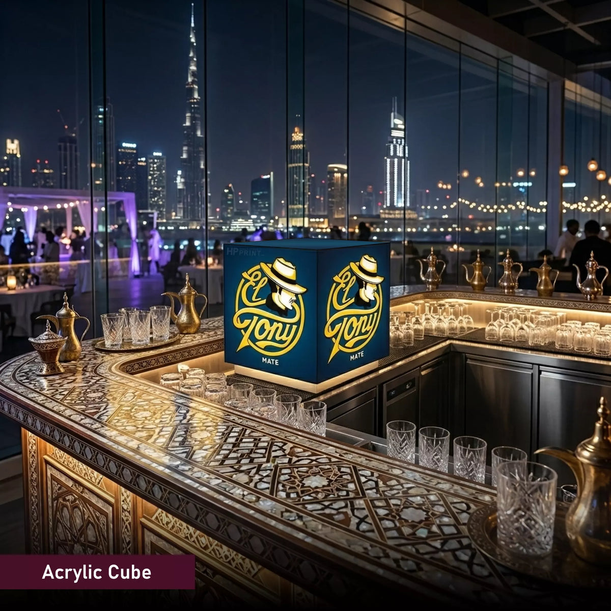 Acrylic cube with 'El Tony' branding on a bar counter with a city skyline in the background