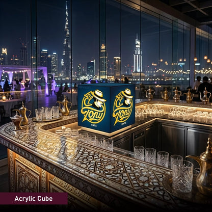 Acrylic cube with 'El Tony' branding on a bar counter with a city skyline in the background