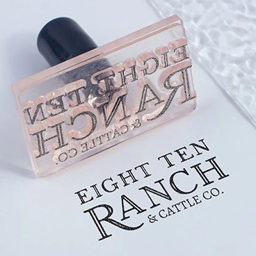 An acrylic stamp with a company name 'EIGHT TEN RANCH & CATTLE CO.' printed on a piece of paper.