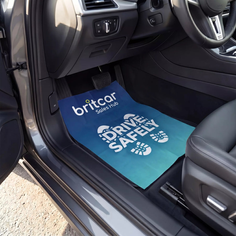 Car interior with a blue mat featuring 'britcar Sales Hub' and 'Drive Safely' text.