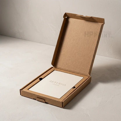 An open brown cardboard presentation box on a light gray surface, containing a white card printed with the brand name AETERNA.