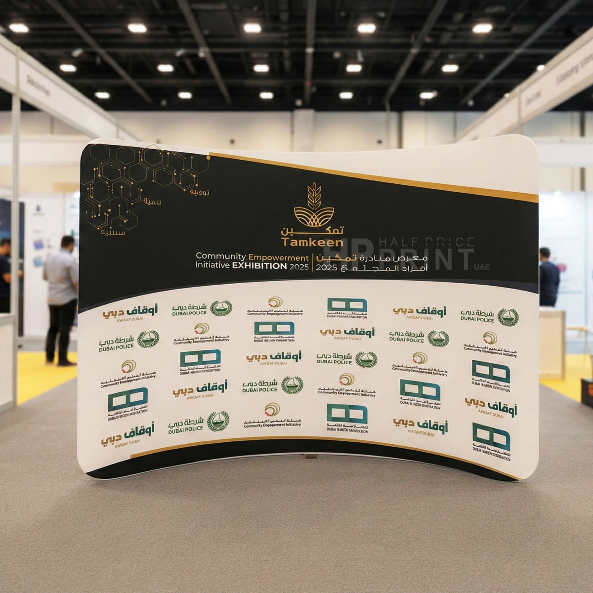 Exhibition stand with multiple logos at an event, featuring the Tamkeen logo.