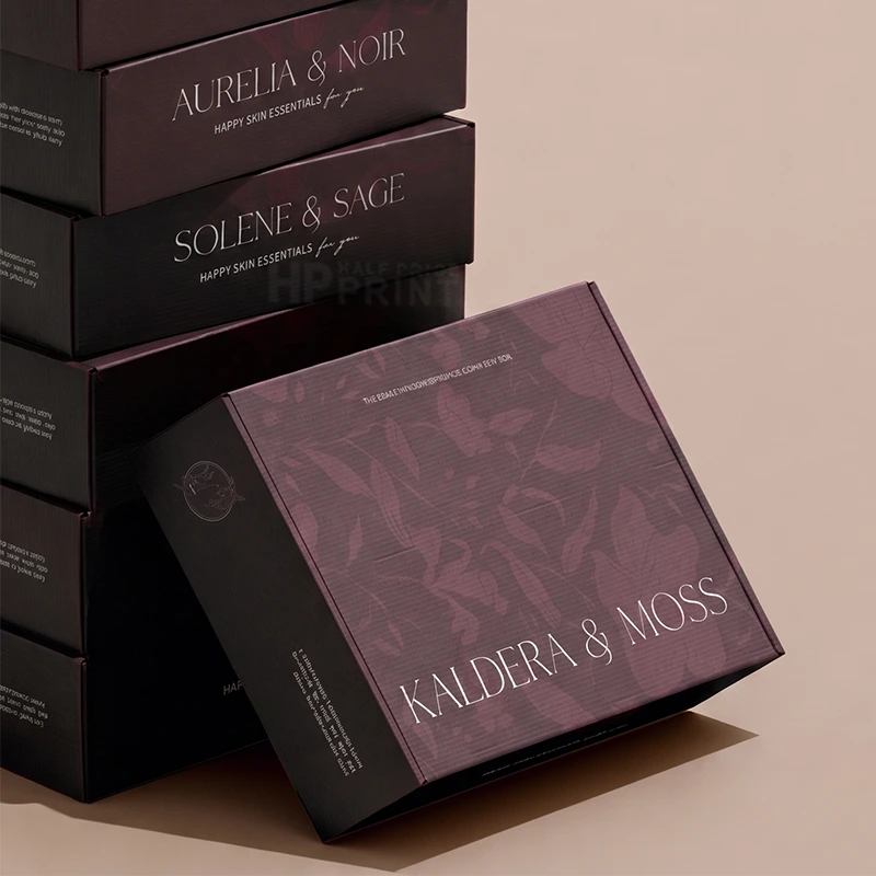 A luxury product packaging display featuring stacked and leaning dark plum-colored boxes with elegant white typography. The front box prominently displays the brand name 'KALDERA & MOSS' alongside the scent 'KALDERA & MOSS SCENTS BY EEA'.