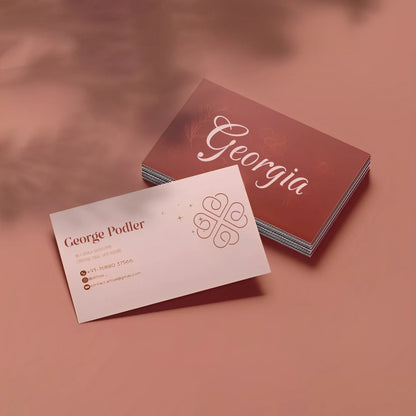 Matte laminated business cards with elegant typography and logo on a pink background, Dubai printing.