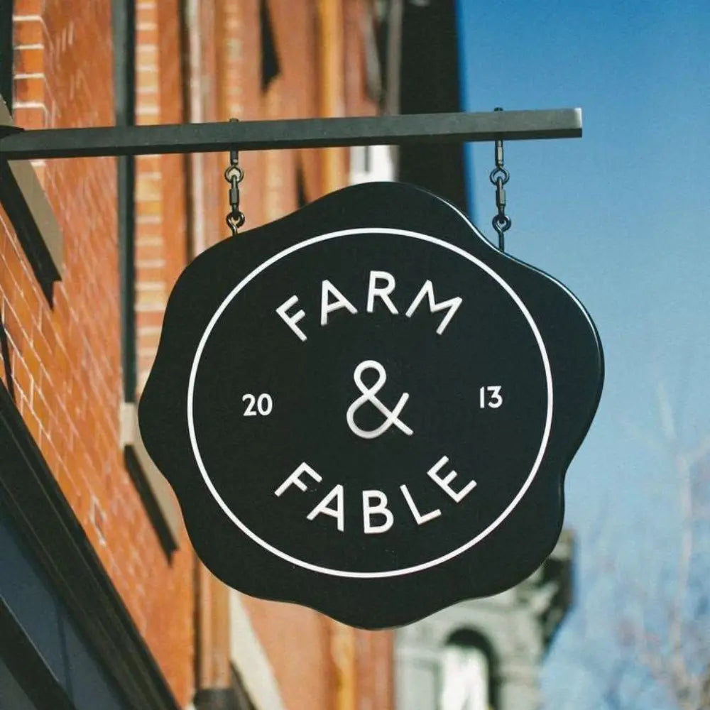 Black sign with 'Farm & Fable' on a building exterior