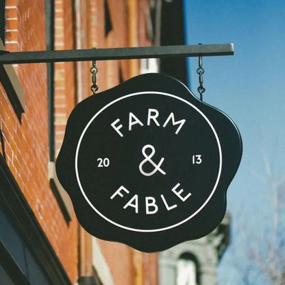 Black sign with 'Farm & Fable' on a building exterior