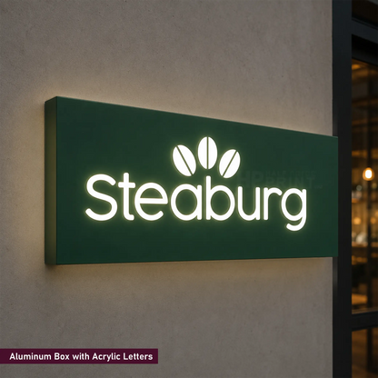 A rectangular illuminated sign mounted on a beige wall, featuring the brand name 'Steburg' in bright white acrylic letters on a dark green aluminum background. A small text label at the bottom left reads 'Aluminum Box with Acrylic Letters.