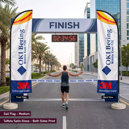 Man crossing a finish line with OKI Bering and 3M branding on sail flags.